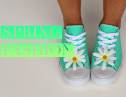 A lady is showing off spring fashion in a pair of pastel green Chuck Taylor's with a daisy in the laces of each shoe.