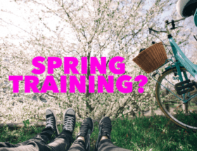 fitness tips: two people are laying on their backs in the grass with a bicycle parked next to them. The cherry blossoms are blooming from a tree in front of them.