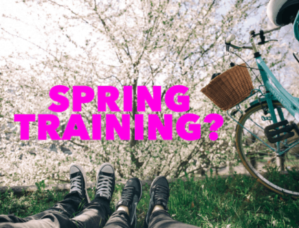 fitness tips: two people are laying on their backs in the grass with a bicycle parked next to them. The cherry blossoms are blooming from a tree in front of them.
