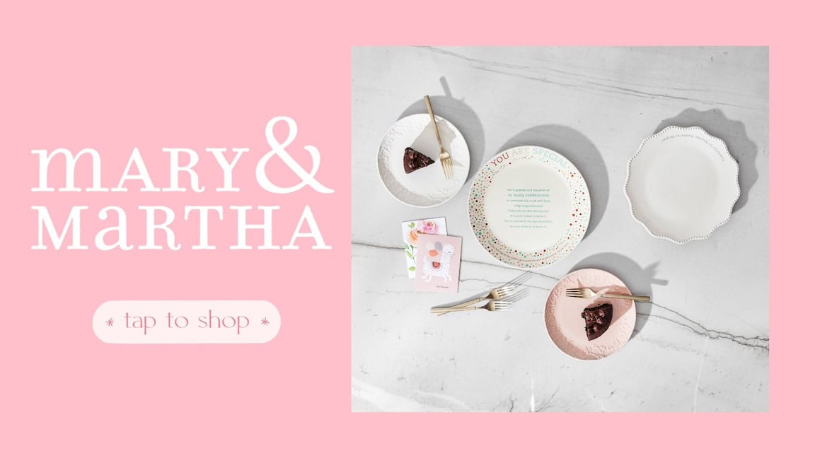 Various Mary & Martha plates with slices of cake on a marble counter with gold-plated forks and two birthday cards