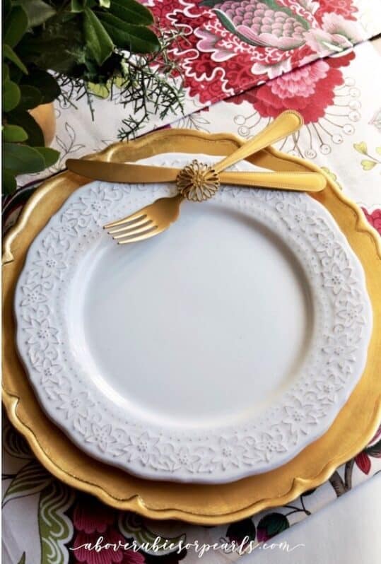 A gold fork and knife placed on a charger and salad plate