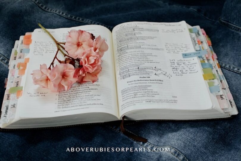 An open Bible with notes written in it and a bouquet of flowers on top
