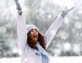 Smiling lady with her arms outstretched in joy on a snowy day