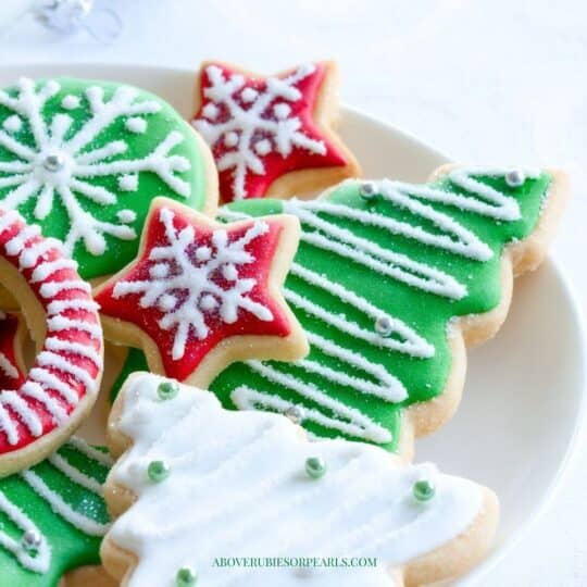 a plate of Christmas sugar cookies cut out in the shape of trees, stars, and snowflakes