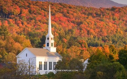 A white church with fall foliage all around