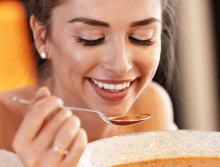 smiling lady eating a bowl of soup