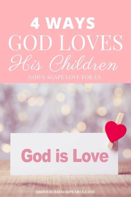 A clothes pin with a red heart attached to it is clipped on a sign that says, 'God is Love.' Twinkling lights are in the background.