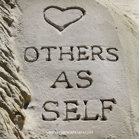 A heart drawn in the sand above the words 'others as self'