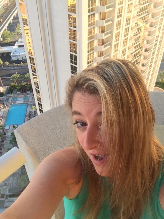 Proverbs 31 business woman selfie in a green tank top with a skyscraper in the background.