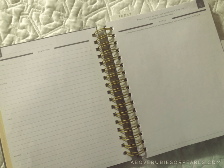 A spiral-bound planner is open on a bed covered in a white quilted bedspread. On the left is space to take notes on a Devotion. On the right is a blank page to take notes with a scripture at the top of the page.