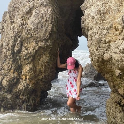 I'm standing under an arch carved out of rock at El Matador Beach. The water has risen and soaked the bottom of my sun dress.