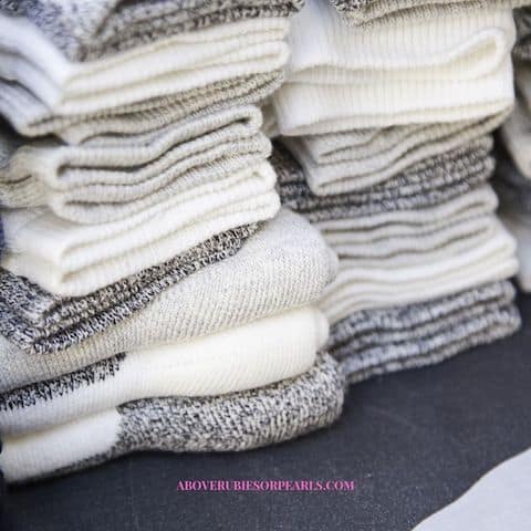 Stacks of white, thick socks with gray heels wait on a table.