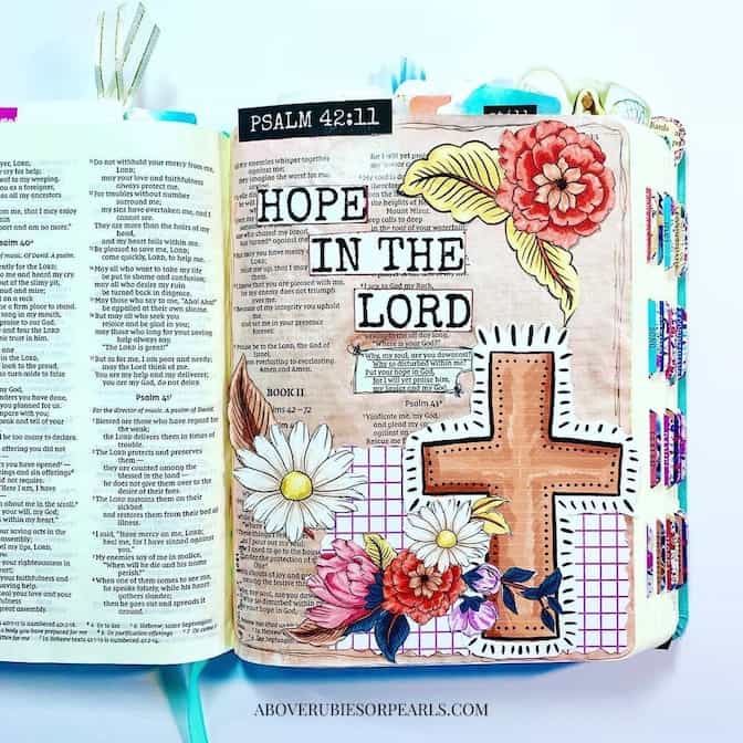 The Holy Bible is open to a page where it has been illustrated with a cross and flowers and the words 'Hope in the Lord.'
