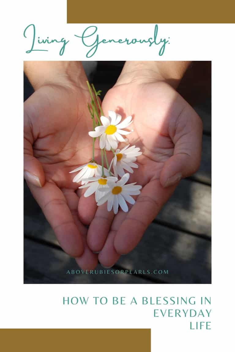 Hands cupped together holding small white flowers with sunlight across them on a wooden surface.
