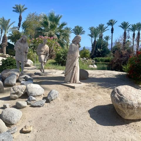 Statues of two disciples following Jesus along The Walk at Shields Date Garden, set among natural plants and winding garden paths.