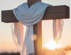 Wooden cross draped with a white cloth at sunrise, symbolizing true confidence in Christ through the Cross