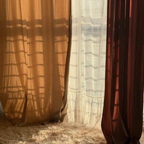 Sunlight streaming through sheer curtains with soft pink-toned drapes and a white shag rug, creating a calm and peaceful closing atmosphere.
